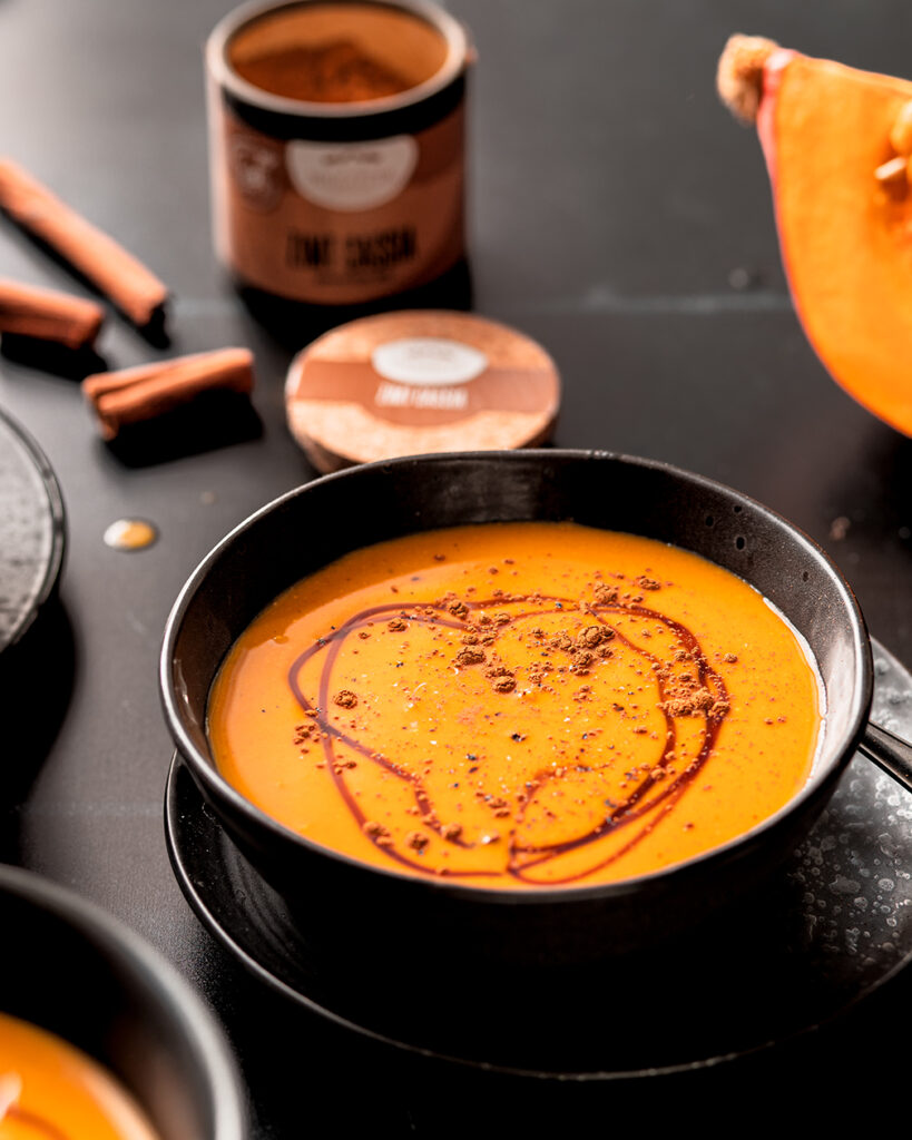 Vegane Kürbissuppe mit Zimt in dunklen Schüsseln