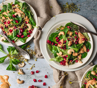 Feldsalat auf Tellern mit Granatapfelkernen und Dressing