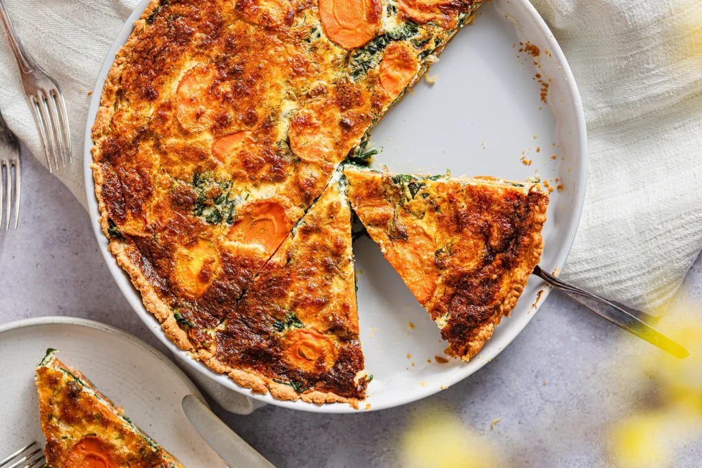 Möhren-Spinat-Quiche angeschnitten in weißer Form