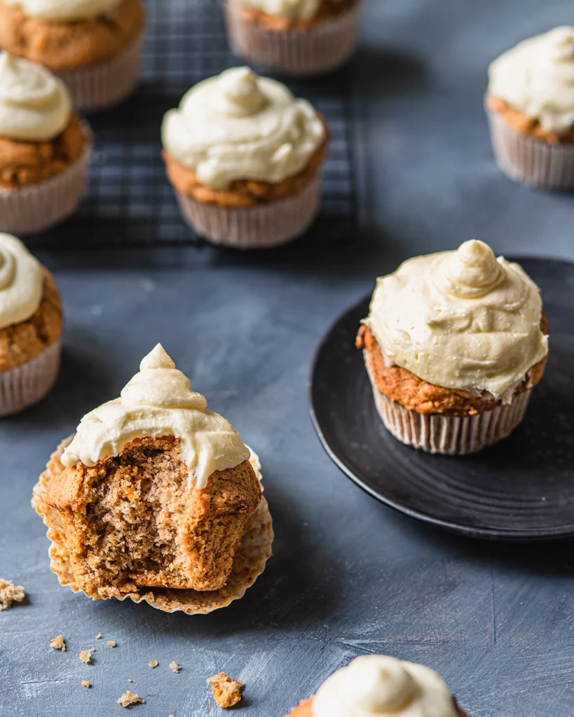 saftige Möhrenmuffins mit Frosting auf Teller und dunklem Tisch