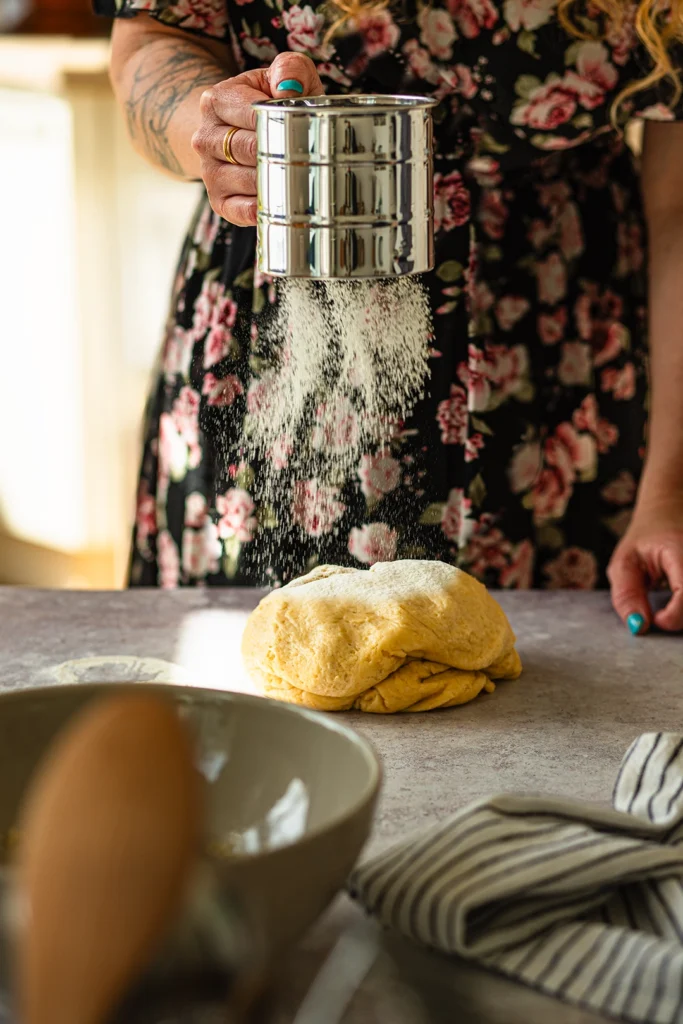 Mehl wird auf Hefeteig des Butterkuchens gestäubt