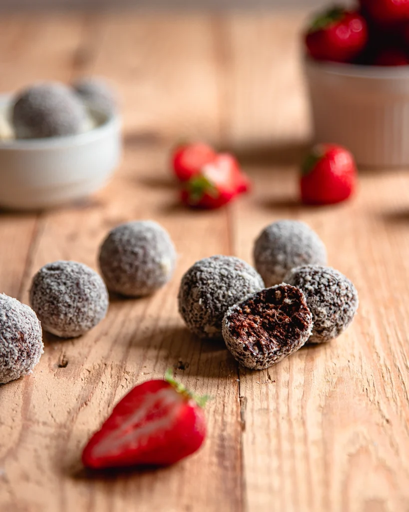 Schwedische Chokladbollar mit frischen Erdbeeren auf Holztisch