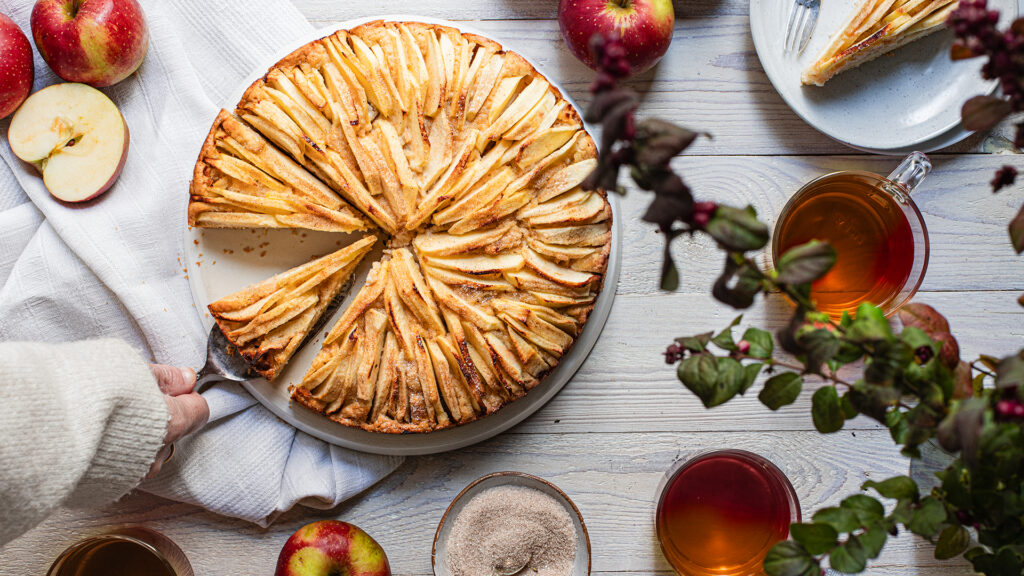 Apfel-Marzipan-Kuchen auf hellem Holztisch in herbstlichem Setting