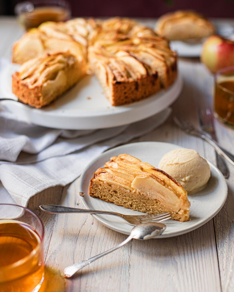 Ein Stück Apfelkuchen mit Marzipan auf Teller mit Vanilleeis