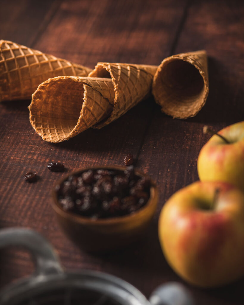 Eiswaffeln, Äpfel und Rosinen auf Holztisch