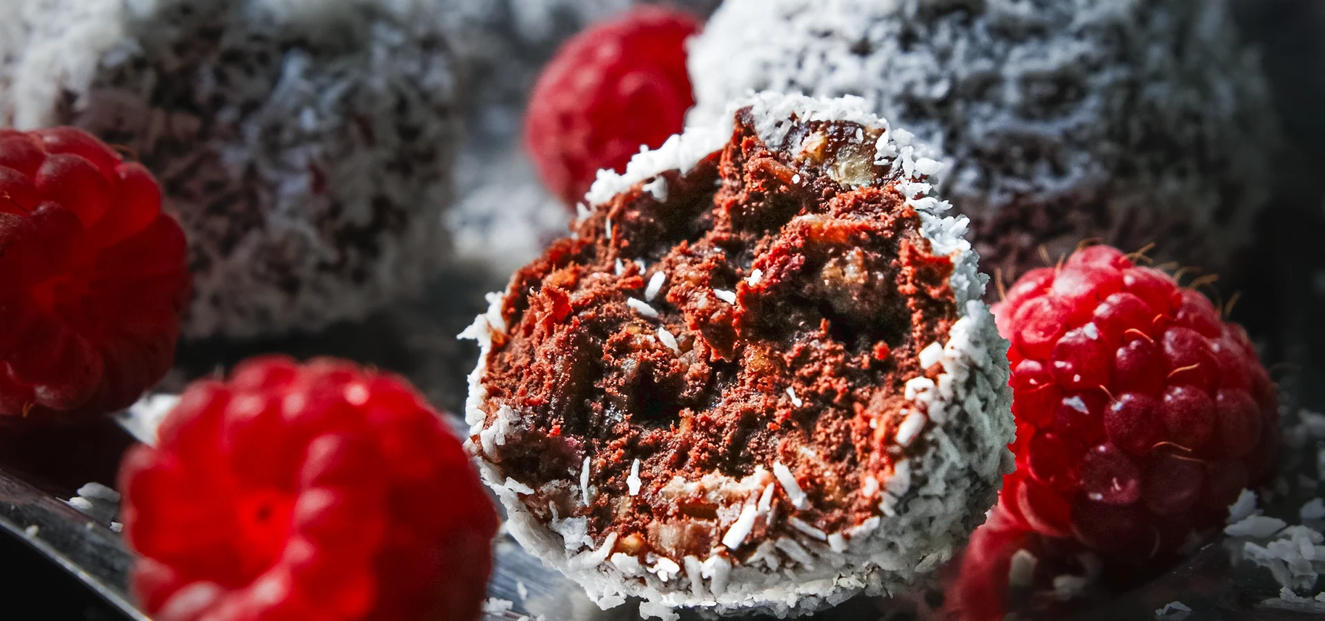 Lotte-and-Food_Food-Fotografie_Chokladbollar-Himbeer_MG_0246-2 Nahaufnahme von schwedischen Chokladbollar mit Himbeeren – schokoladige Haferkugeln mit frischen Himbeeren, auf dunklem Untergrund und silbernen kleinen Tablett